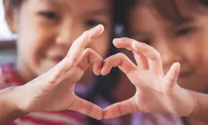 Two cute asian child girls making heart shape with hands together